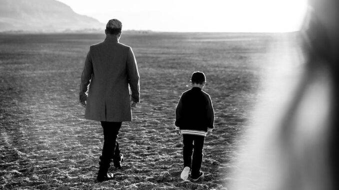 black and white photo of a person walking with a child